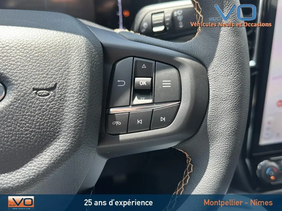 Gros plan sur le volant multifonctions noir du Ford Ranger 2025 avec surpiqûres marron et commandes intégrées.