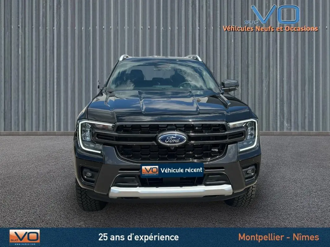 Vue frontale du Ford Ranger Wildtrak noir 2025 avec calandre imposante et barres de toit visibles.