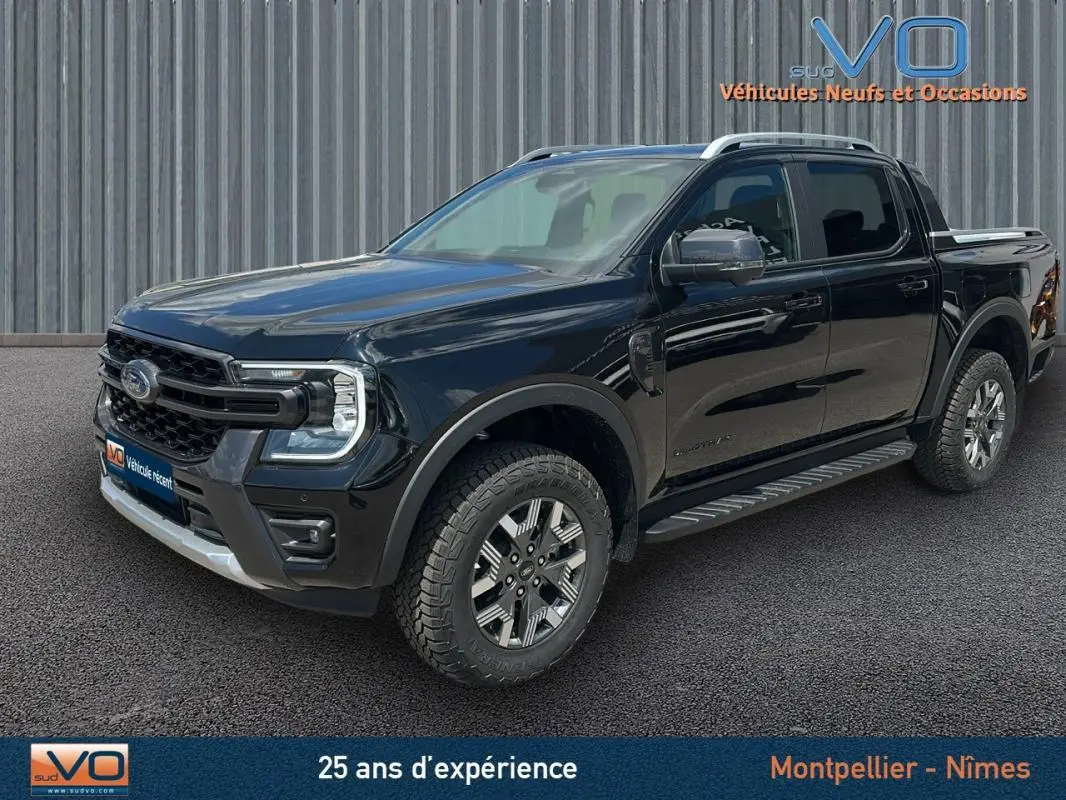 Vue 3/4 avant du Ford Ranger Wildtrak noir 2025 avec barres de toit, marchepieds et jantes alliage 18 pouces.