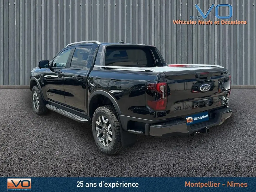 Vue 3/4 arrière côté gauche du Ford Ranger Wildtrak noir avec barres de toit et jantes alliage 18 pouces.