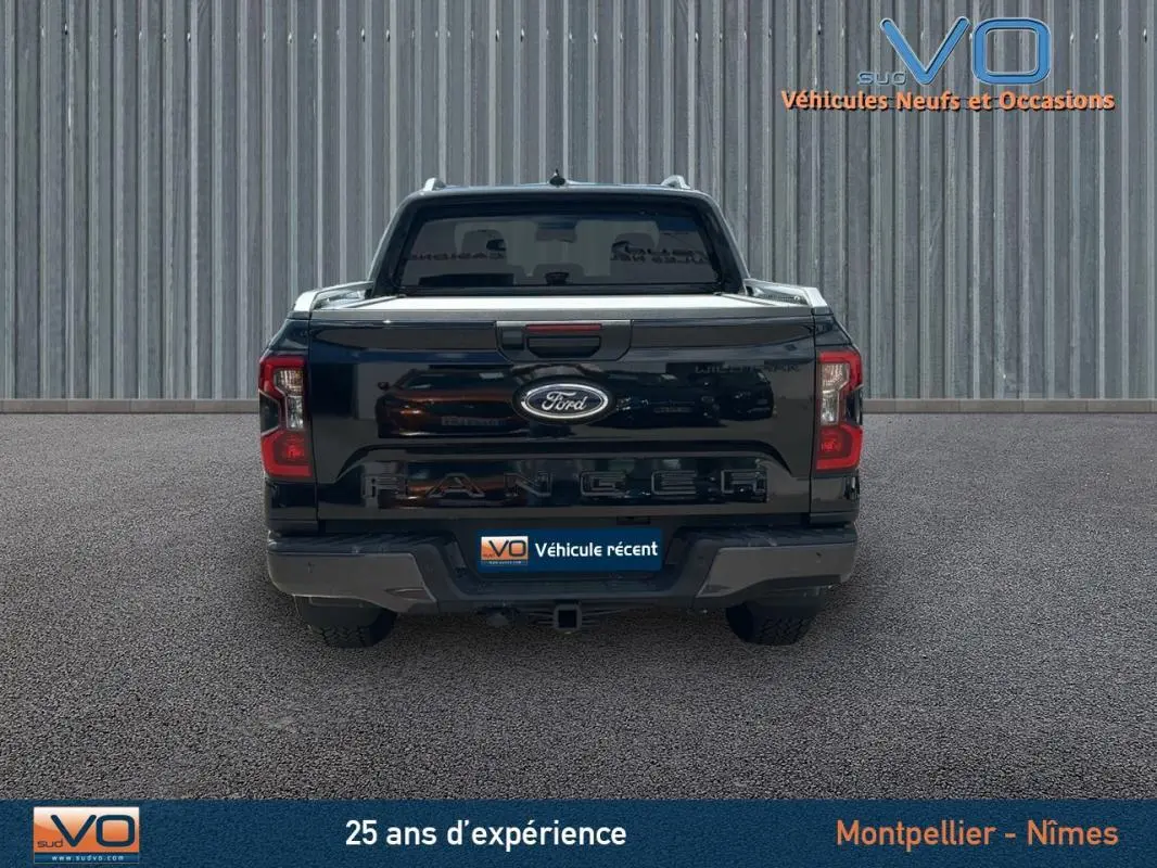 Vue arrière du Ford Ranger Wildtrak noir 2025 avec barres de toit et vitres surteintées visibles.