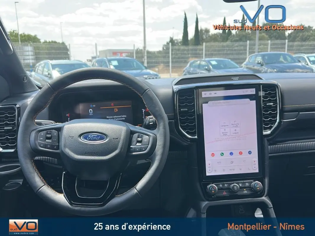 Vue intérieure centrée sur le volant multifonctions et l'écran tactile vertical du Ford Ranger Wildtrak noir 2025.
