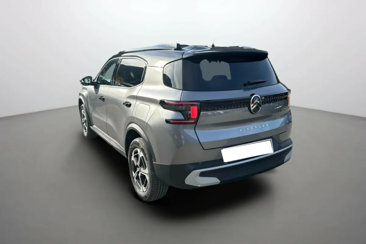 Vue 3/4 arrière d'un Citroën C3 Aircross gris mercury avec toit noir et vitres arrière surteintées.