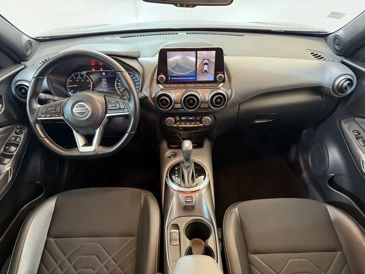 Intérieur du Nissan Juke Tekna 2021, vue frontale sur tableau de bord avec écran tactile et volant cuir noir.