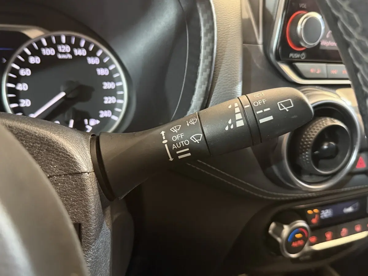 Gros plan sur la commande d’essuie-glace à gauche du volant dans l’habitacle gris du Nissan Juke Tekna 2021.