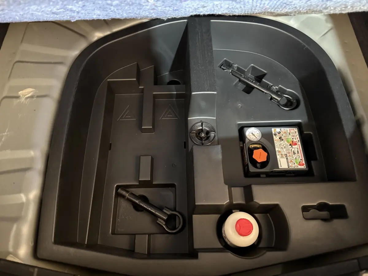Compartiment de rangement sous le coffre du Nissan Juke gris clair 2021 avec kit de réparation pneus et outils.