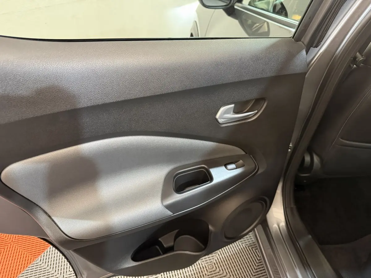 Vue intérieure côté gauche de la porte arrière gris clair du Nissan Juke 2021 avec poignée et commande de fenêtre.
