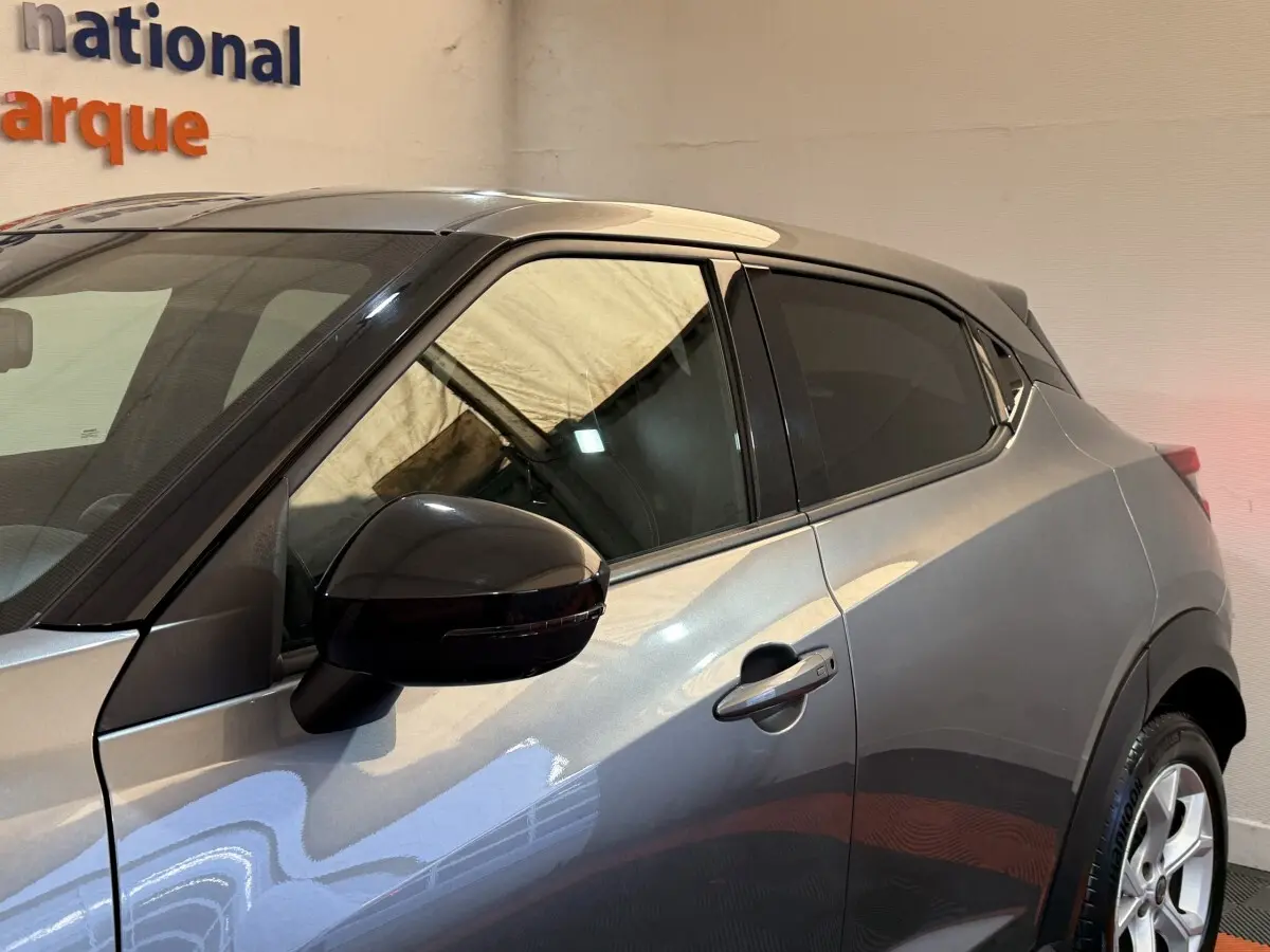 Vue latérale côté gauche d'un Nissan Juke gris clair avec rétroviseur noir et vitres teintées.