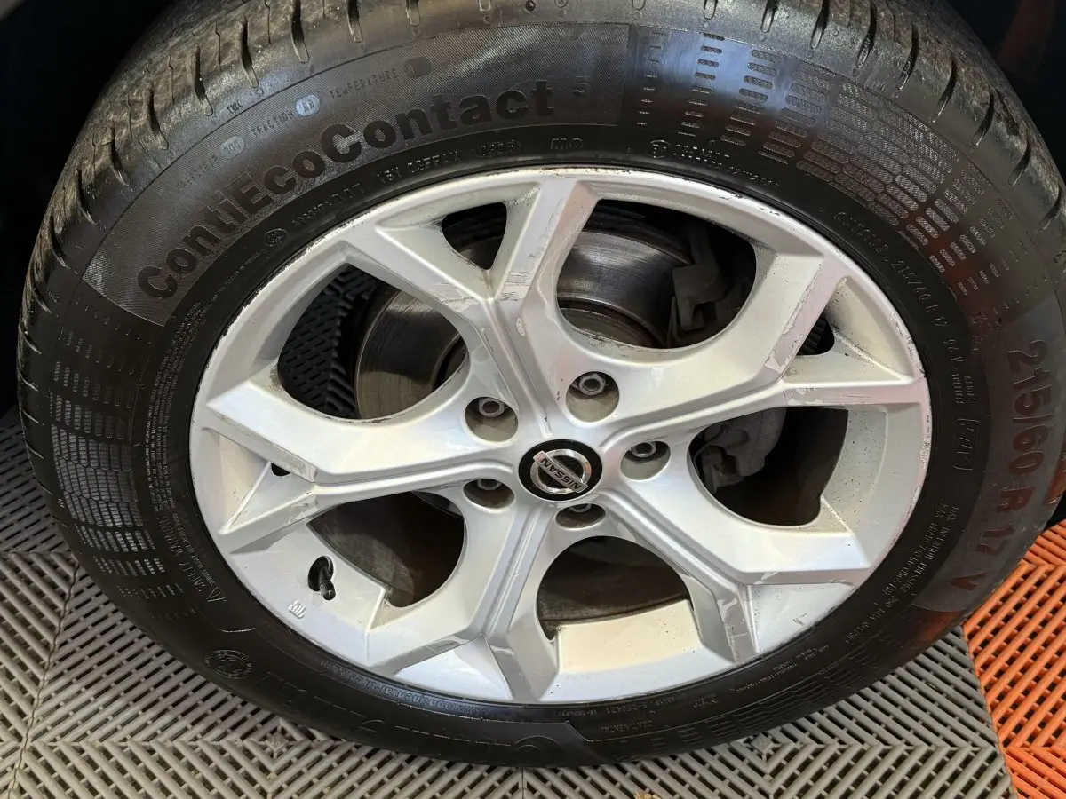 Vue de profil côté gauche d'un Nissan Juke gris clair 2021 avec jantes alliage et pneus hiver visibles.