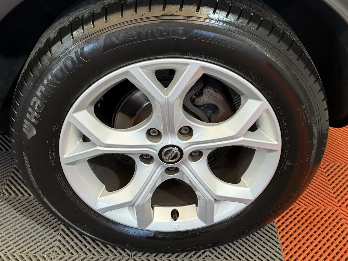 Gros plan sur la roue avant droite du Nissan Juke gris clair 2021 avec jante alliage et pneu neuf.