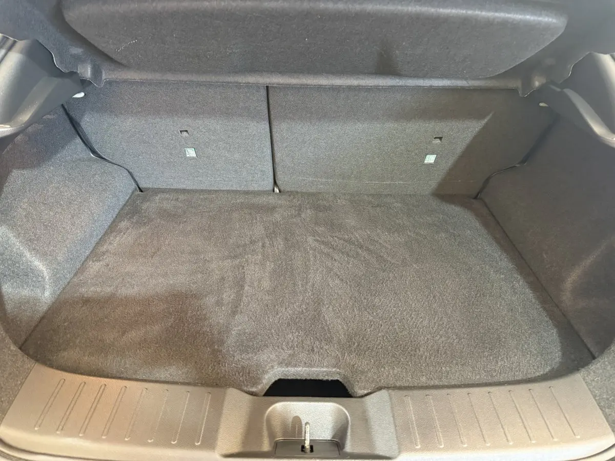 Coffre ouvert du Nissan Juke gris clair 2021, vue intérieure montrant le plancher et la banquette arrière rabattue.