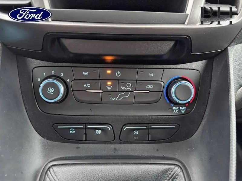 Gros plan sur les commandes de climatisation et d’aide à la conduite du Ford Transit Connect blanc glacier, tableau de bord noir.