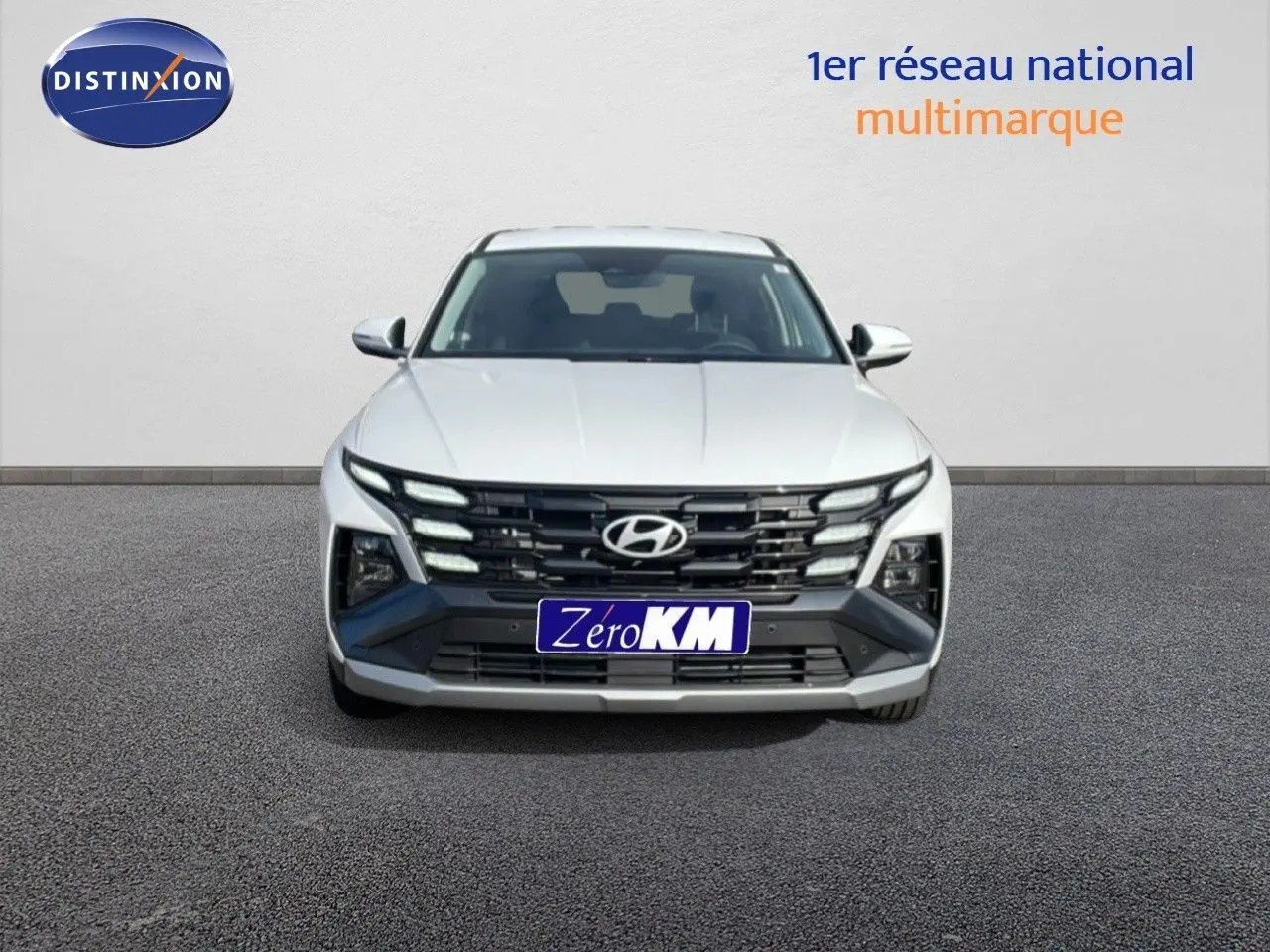 Vue frontale d'un Hyundai Tucson blanc Atlas 2026 avec calandre noire et feux LED distinctifs.
