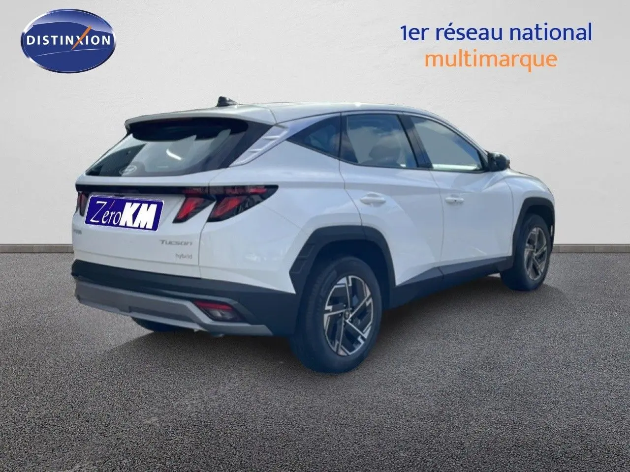Vue 3/4 arrière droite d'un Hyundai Tucson blanc Atlas hybride avec jantes bi-ton et feux arrière LED distinctifs.