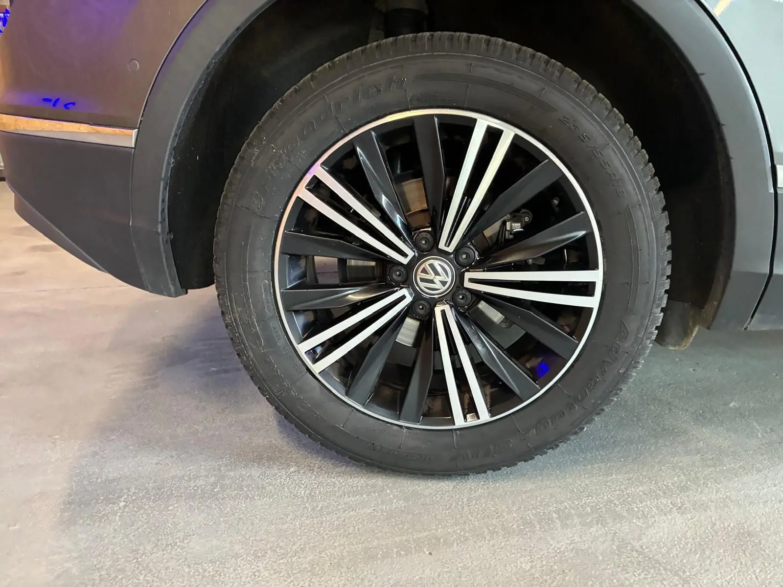 Gros plan sur la roue avant droite du Volkswagen Tiguan gris, mettant en valeur la jante noire et argentée au design moderne.