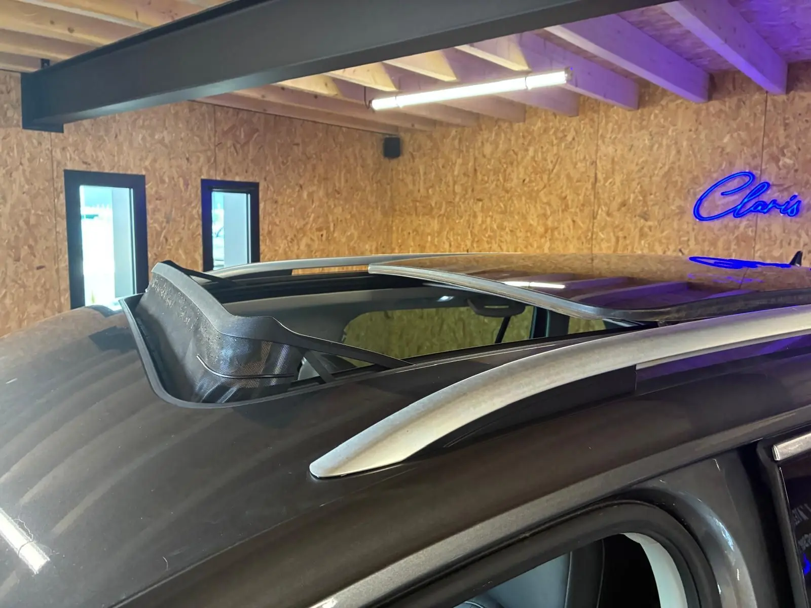 Toit ouvrant ouvert vu de près sur le côté gauche d’un Volkswagen Tiguan gris dans un garage.