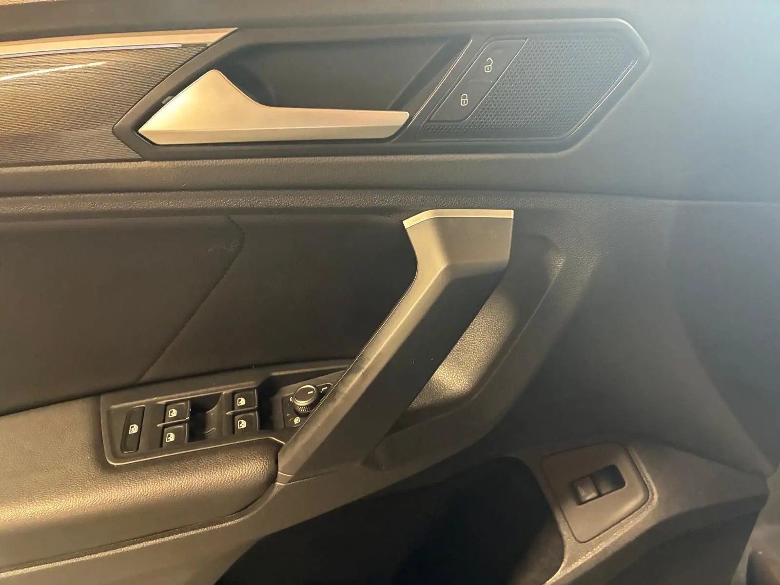 Détail de la porte côté conducteur du Volkswagen Tiguan 2020, montrant les commandes de vitres et la poignée intérieure en noir.