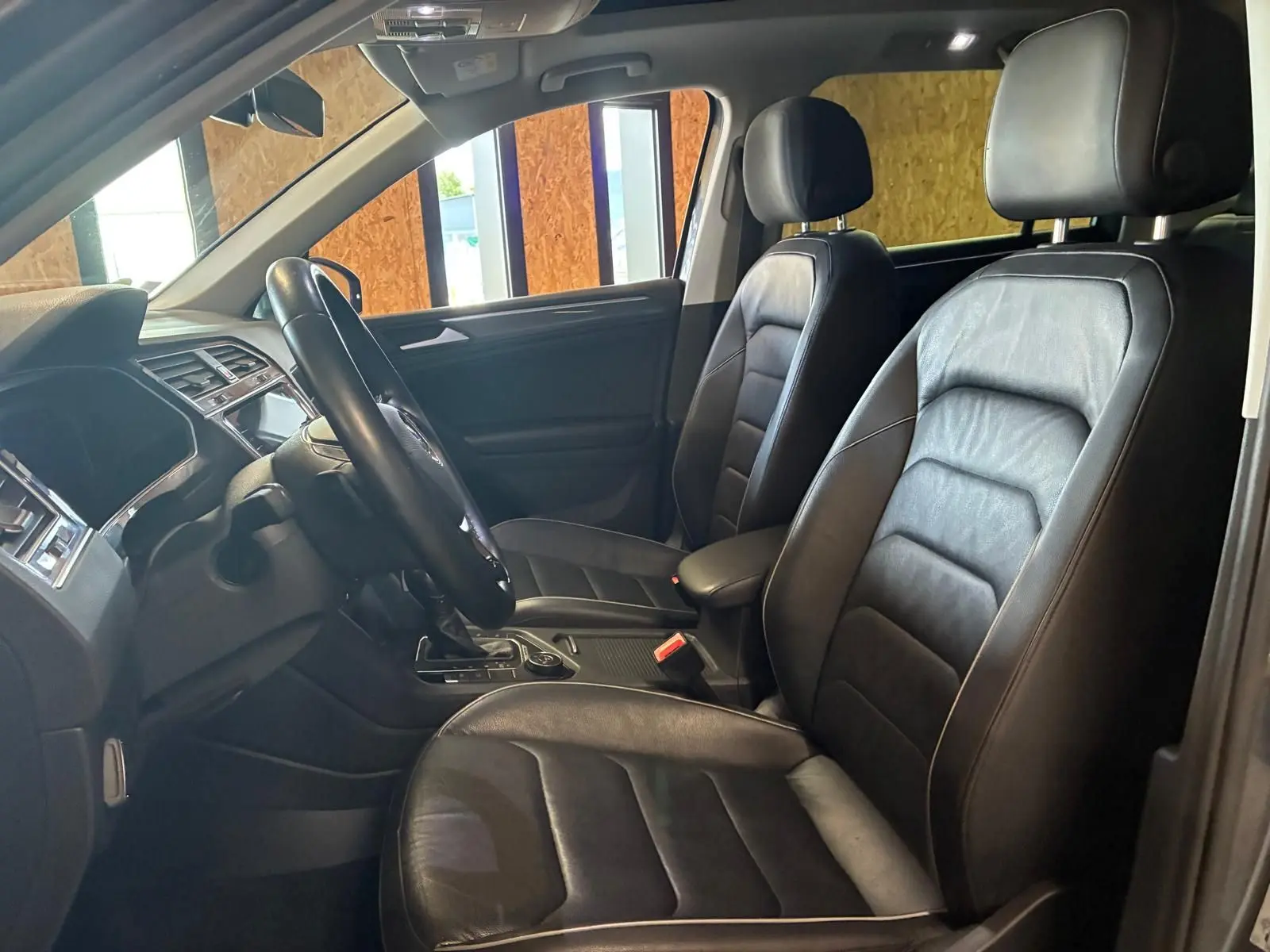 Vue intérieure côté conducteur du Volkswagen Tiguan 2020, sièges en cuir noir et tableau de bord moderne.