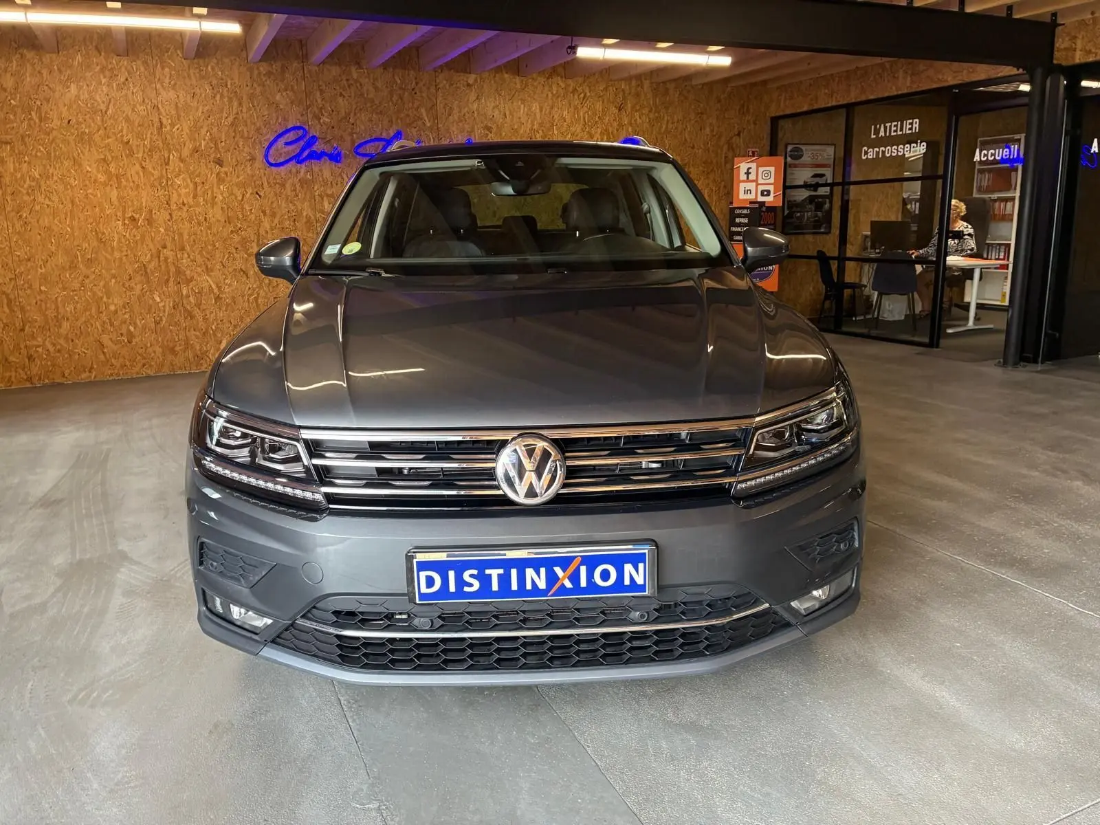 Vue avant d'un Volkswagen Tiguan gris 2020, avec calandre chromée et phares LED, en intérieur showroom.