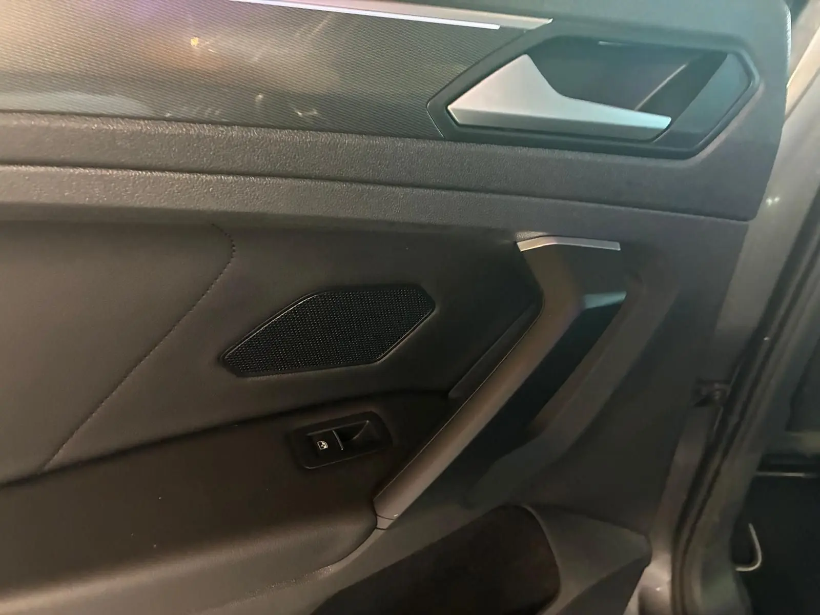 Détail de la porte intérieure côté gauche du Volkswagen Tiguan 2020 gris, avec poignée et commande de vitre.
