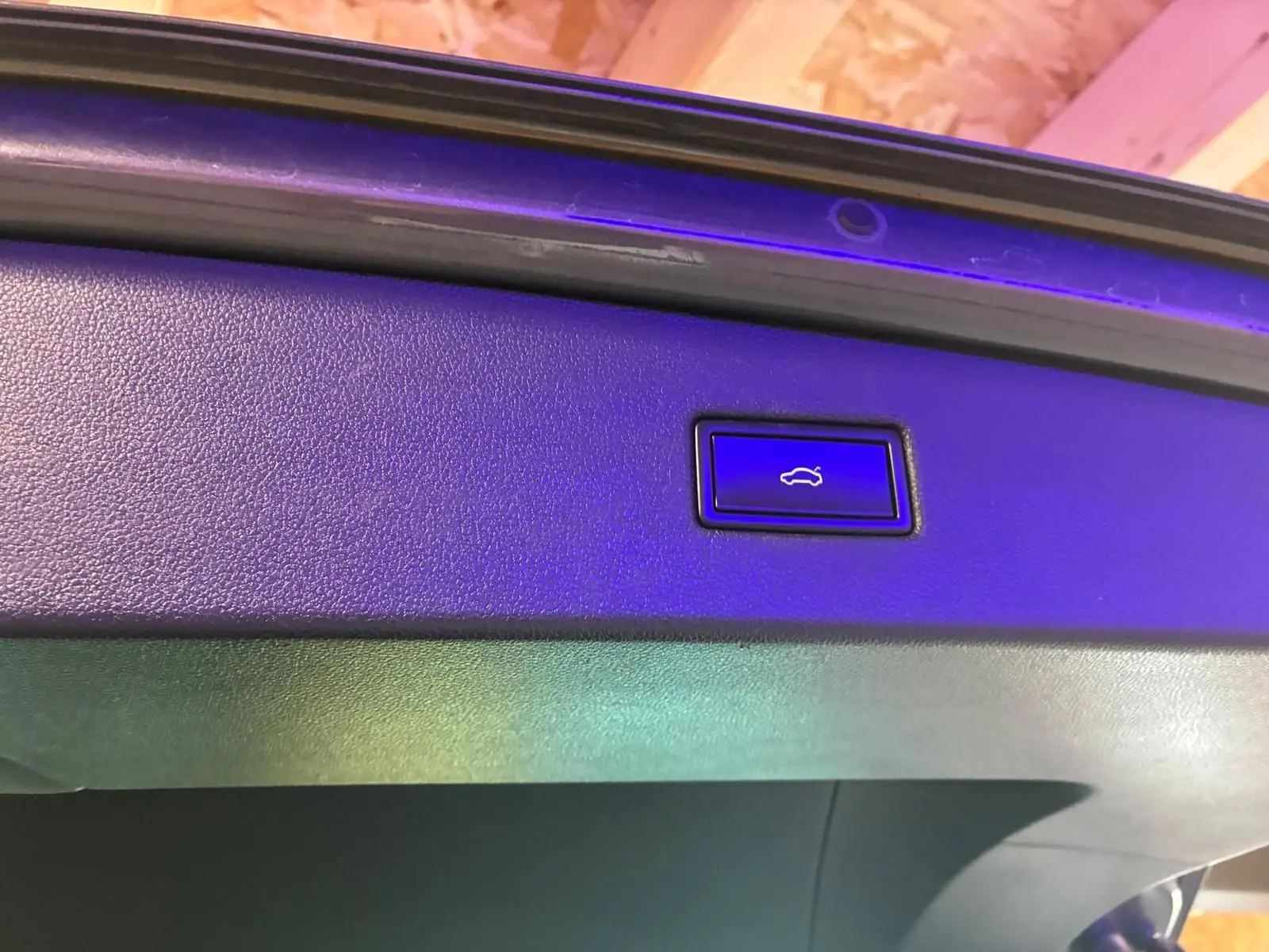 Gros plan sur le bouton d'ouverture électrique du hayon du Volkswagen Tiguan gris, vue intérieure du coffre.