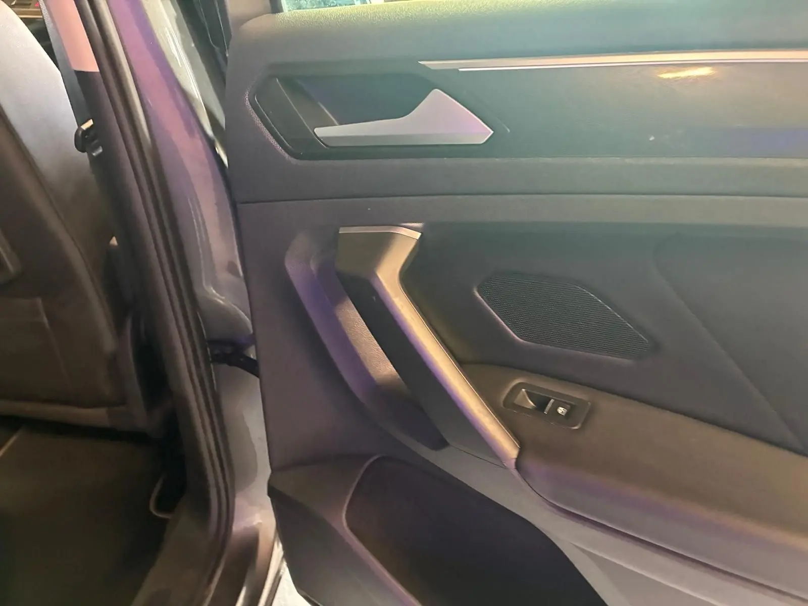 Détail de la porte arrière gauche grise d’un Volkswagen Tiguan 2020 avec poignée et commande de fenêtre.