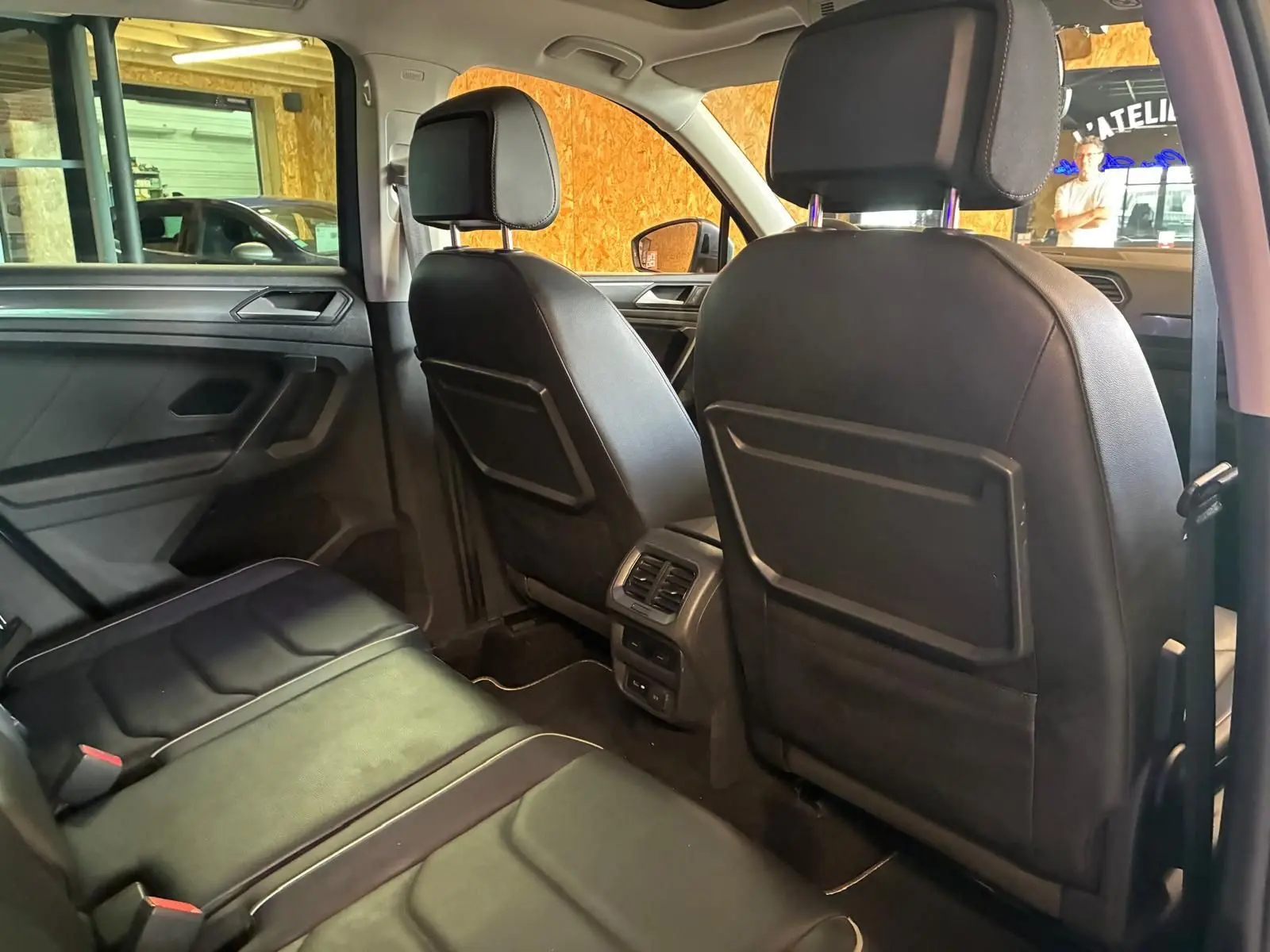 Vue intérieure arrière du Volkswagen Tiguan 2020, sièges en cuir noir et aérateurs centraux visibles.