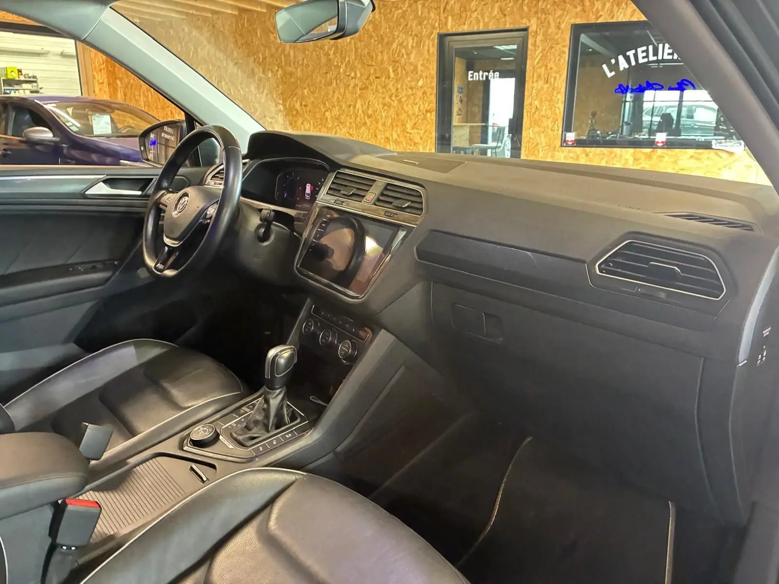 Vue intérieure côté conducteur du Volkswagen Tiguan gris 2020, avec tableau de bord moderne et sellerie cuir noire.