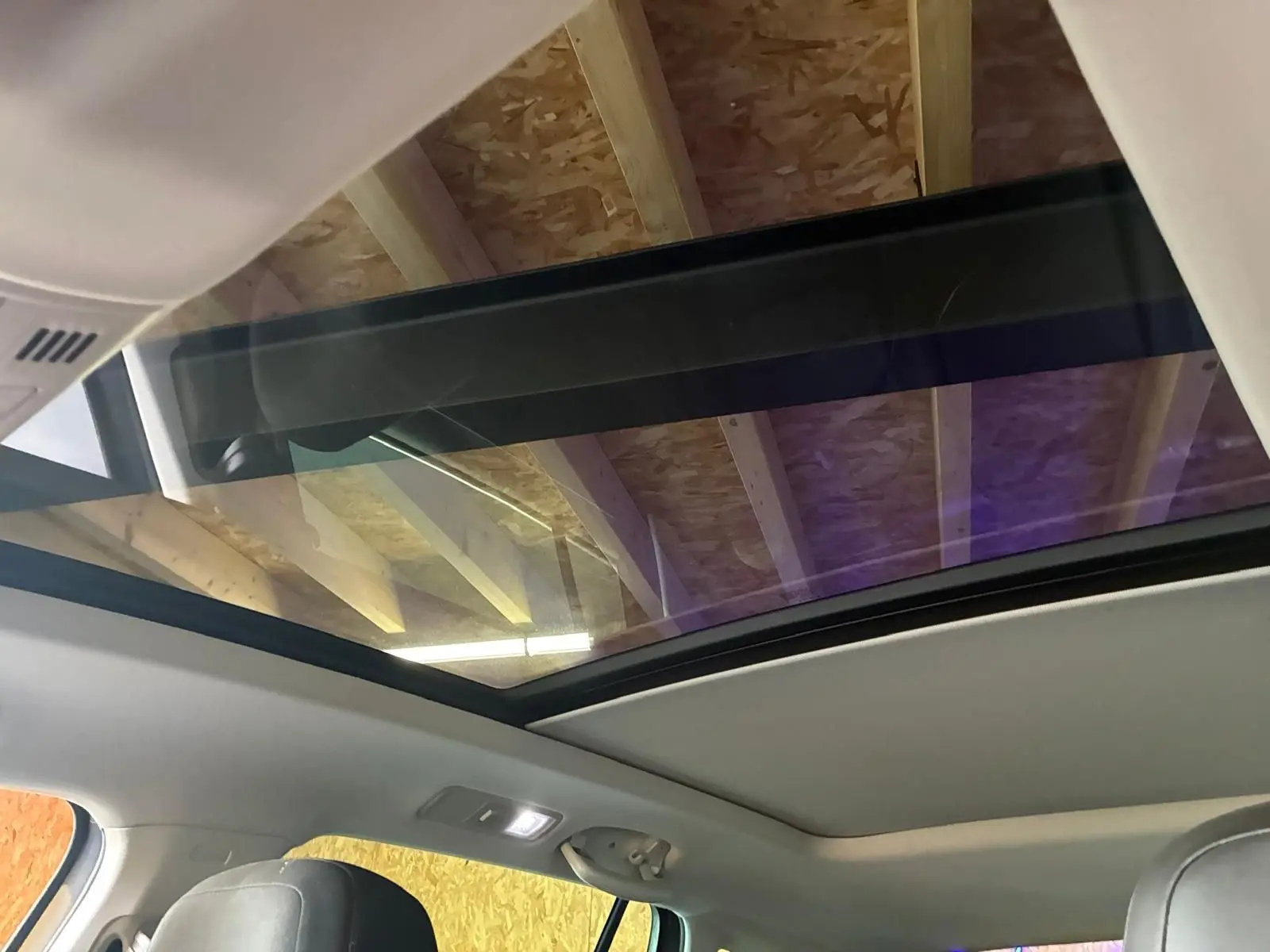 Toit panoramique ouvert vu de l'intérieur sur un Volkswagen Tiguan gris, montrant la partie supérieure et les sièges avant.