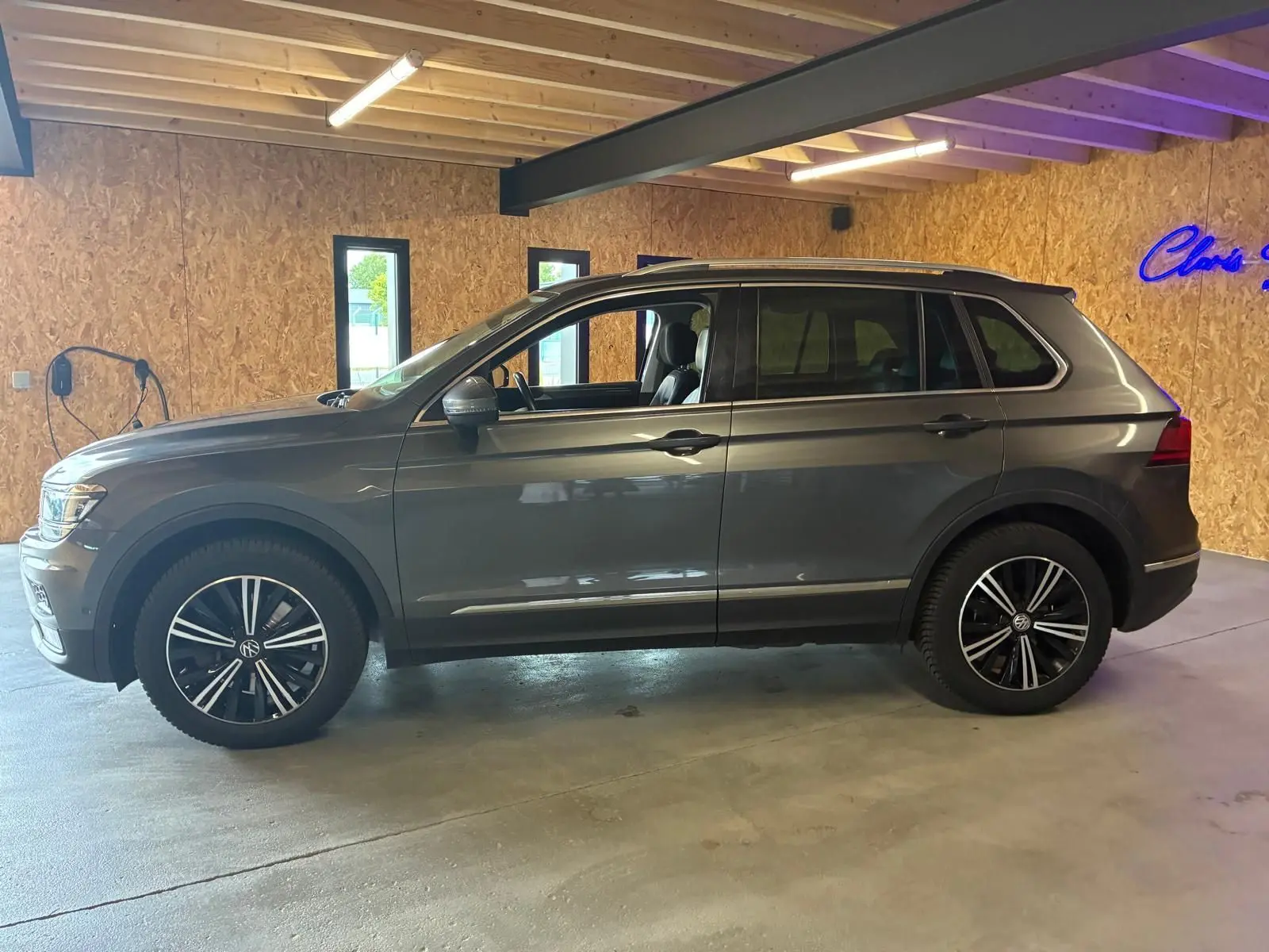 Vue de profil côté gauche d'un Volkswagen Tiguan gris 2020, avec jantes noires et intérieur visible à travers les vitres.
