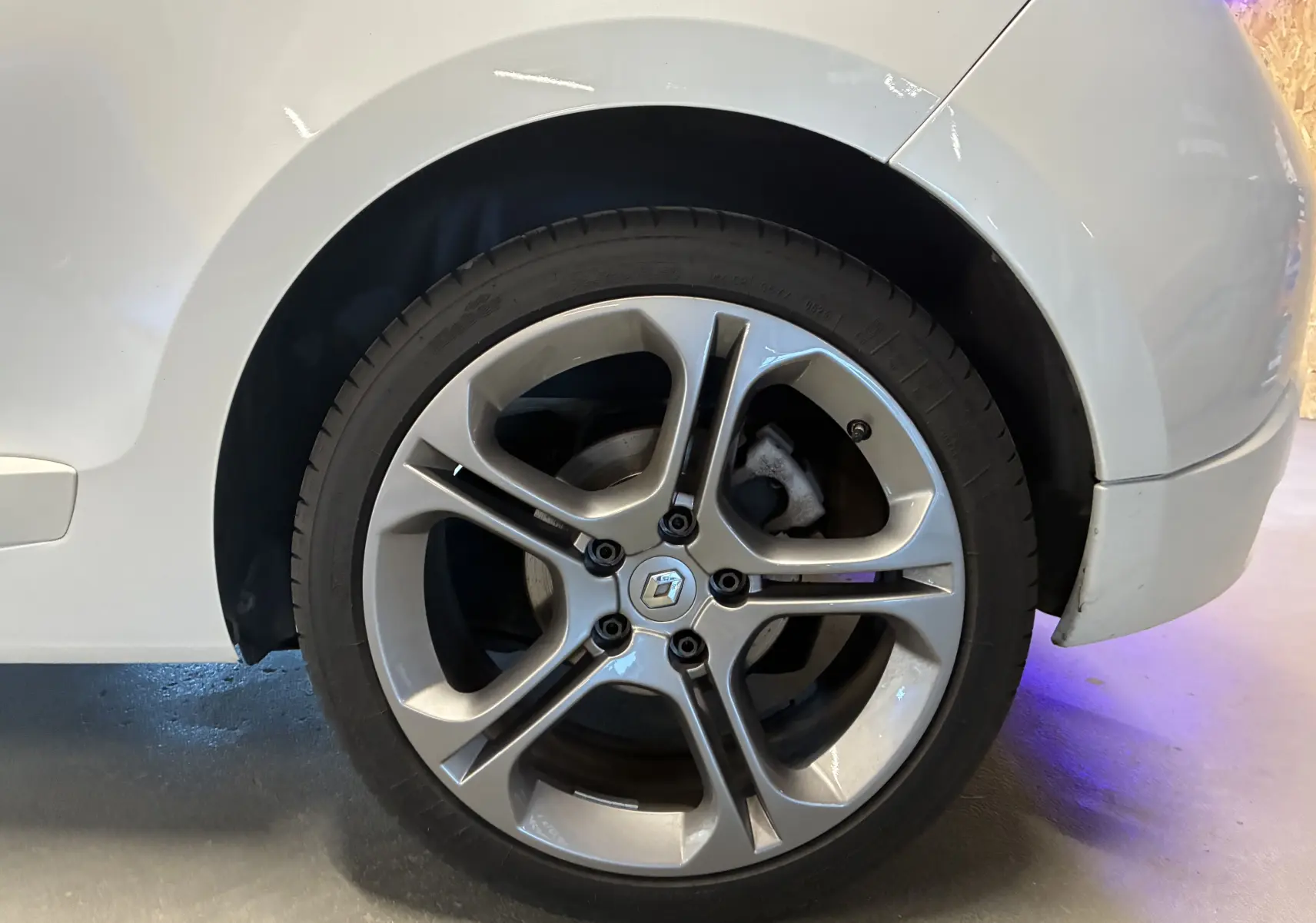 Gros plan sur la roue arrière droite blanche d'une Renault Mégane Coupé 2.0 DCI 165 GT avec jante alliage distinctive.