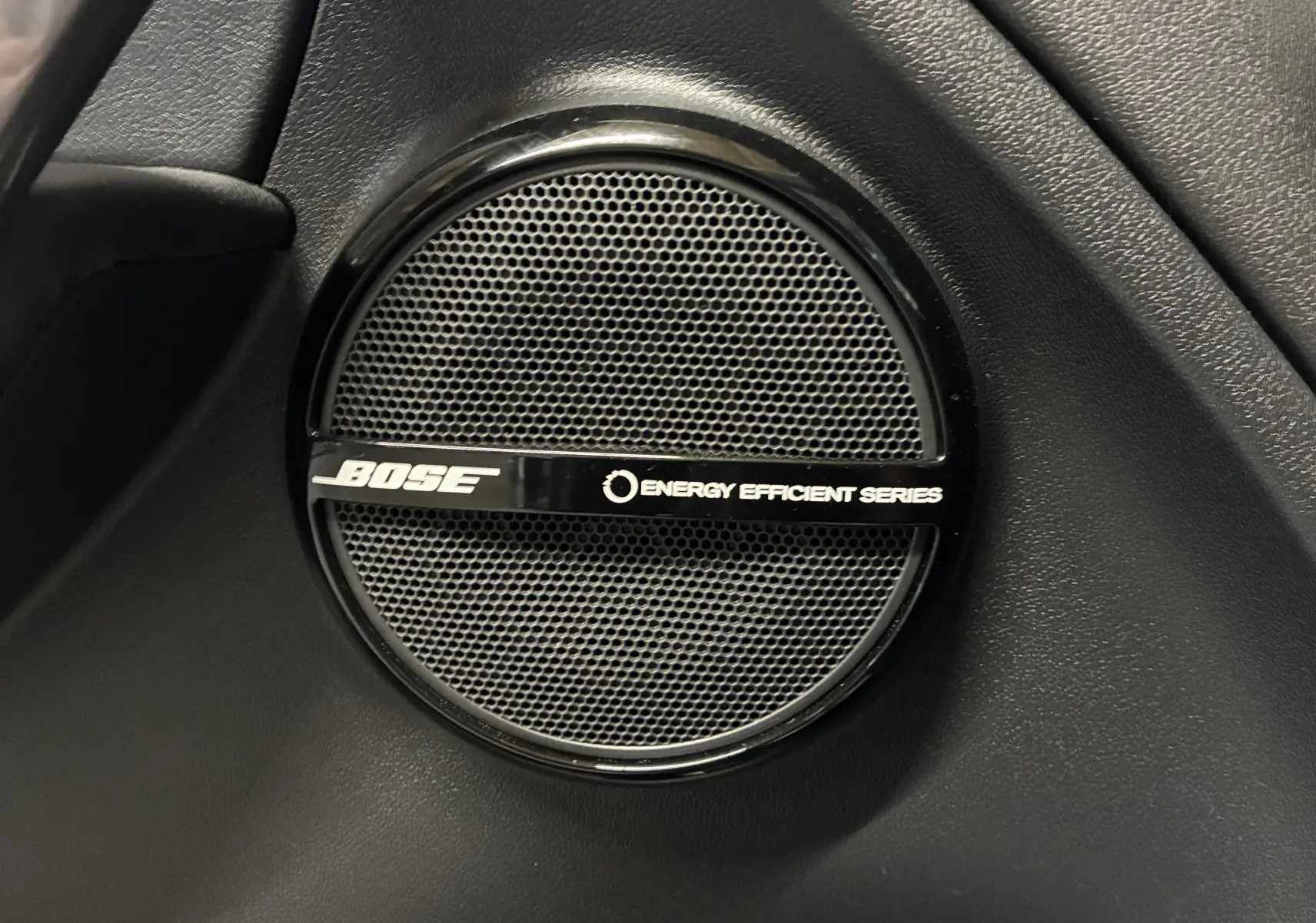 Gros plan sur l'enceinte Bose noire intégrée à l'intérieur de la Renault Mégane Coupé 2.0 DCI 165 GT blanche.