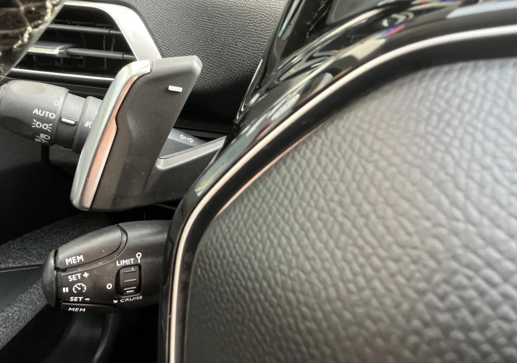 Détail du volant et des commandes de régulateur de vitesse du Peugeot 3008 1.5 BlueHDi blanc, intérieur noir.