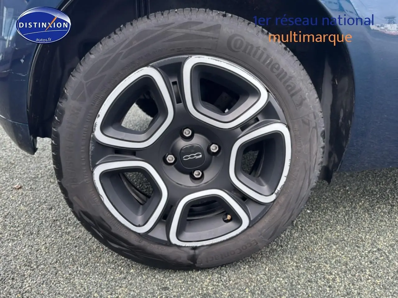 Gros plan sur la roue avant droite avec jante noire et argentée de la FIAT 500 bleu foncé 2023.