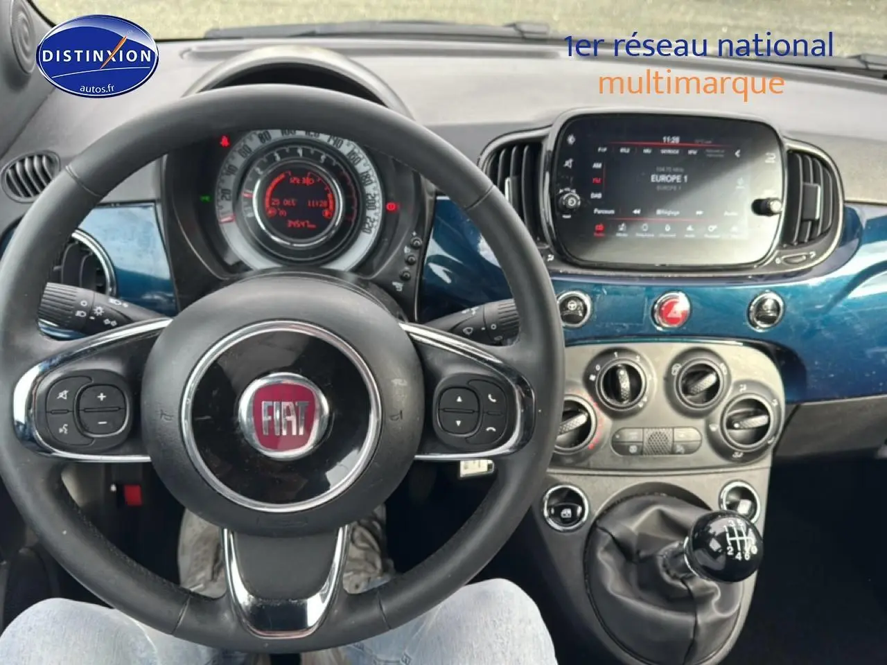 Vue intérieure centrée sur le volant cuir et tableau de bord bleu foncé de la Fiat 500 1.0 70 bsg cult 2023.