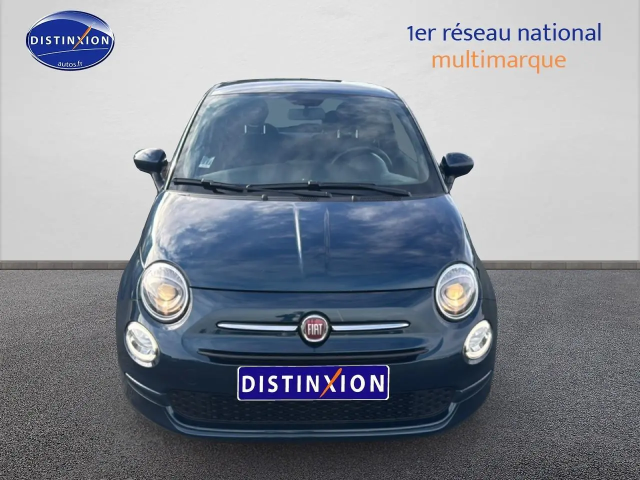 Vue frontale d'une FIAT 500 1.0 70 bsg cult bleu foncé avec phares allumés sur fond neutre.
