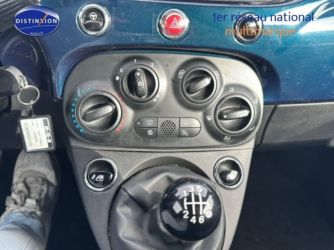 Vue rapprochée du levier de vitesses manuel et des commandes de climatisation sur tableau de bord bleu foncé d’une Fiat 500.