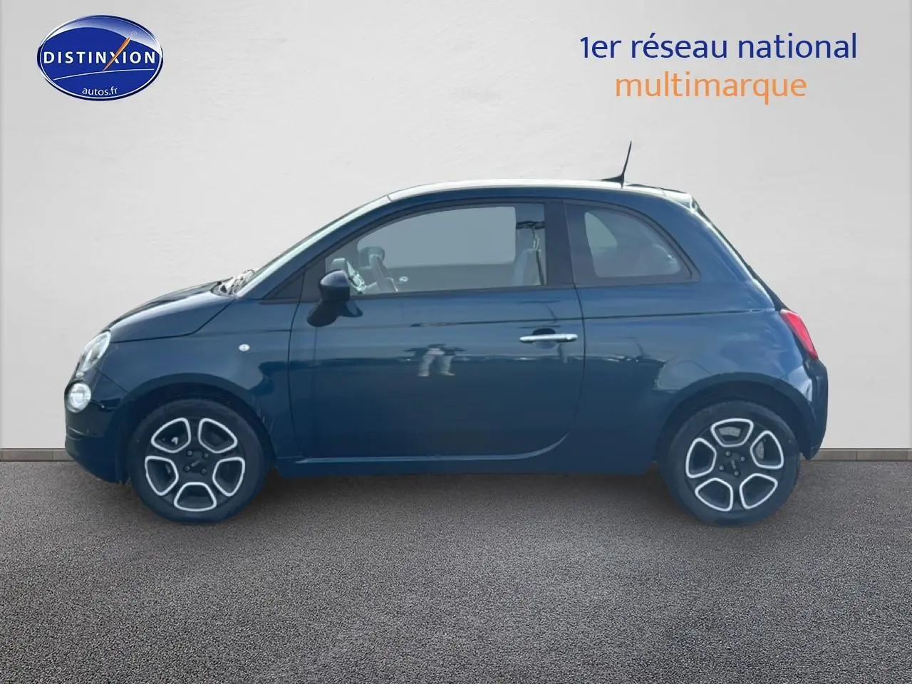 Profil droit d'une FIAT 500 bleu foncé 2023 avec jantes alliage et toit blanc sur fond neutre.