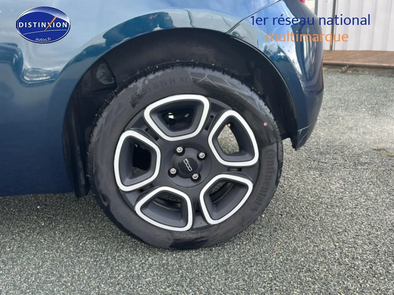 Gros plan sur la roue arrière droite d'une Fiat 500 bleu foncé avec jante au design moderne.