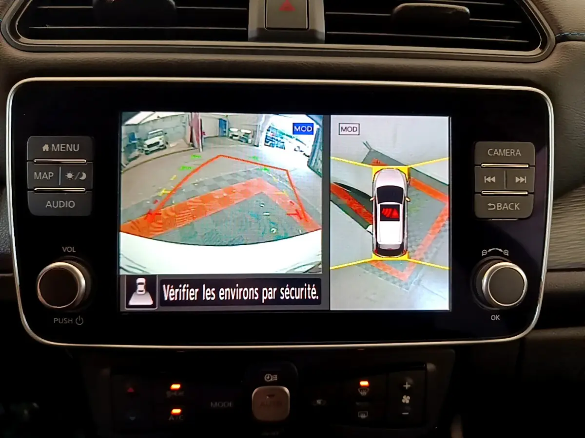 Écran tactile central de la Nissan Leaf blanche 2020 affichant la caméra 360° et l'aide au stationnement en vue arrière.