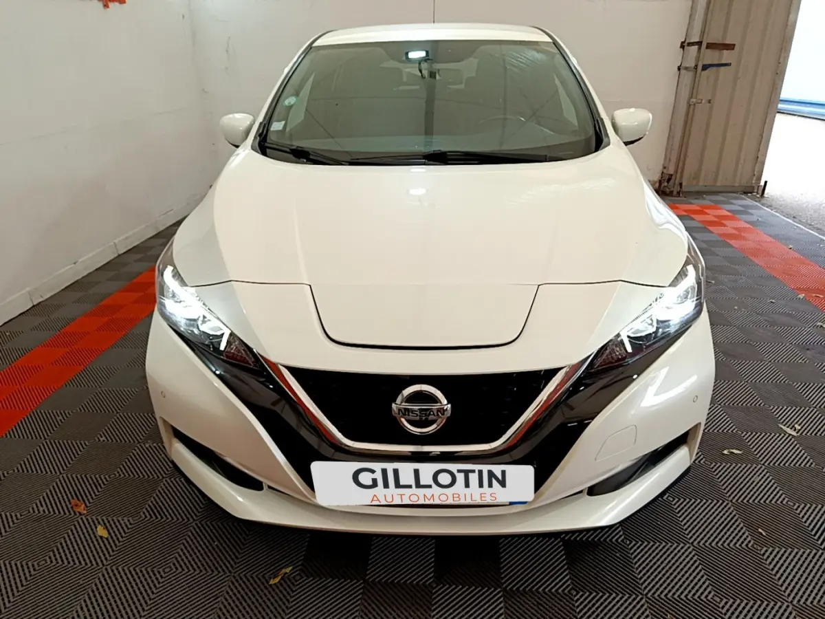 Vue avant d'une Nissan LEAF blanche 62 kWh avec phares LED allumés dans un garage fermé.