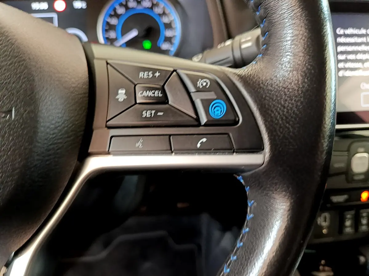 Gros plan sur le côté gauche du volant cuir noir de la Nissan Leaf 62 kWh 2020, avec commandes de régulateur adaptatif.