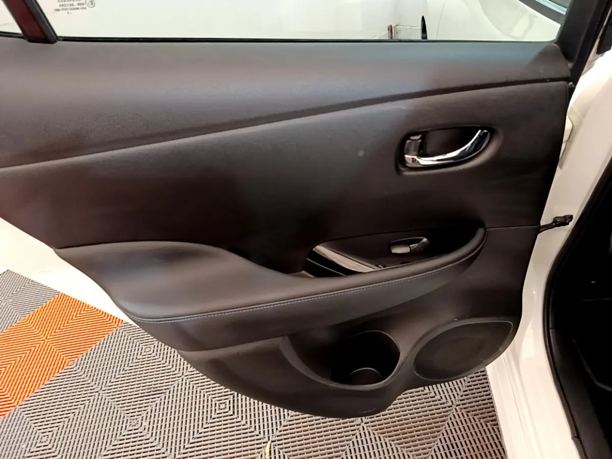 Vue rapprochée de la porte arrière droite noire intérieure d'une Nissan Leaf blanche 2020 avec poignée chromée.