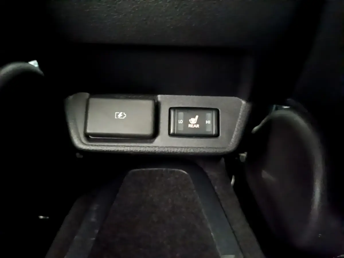 Gros plan sur les commandes noires de chauffage des sièges arrière dans une Nissan Leaf blanche de 2020.