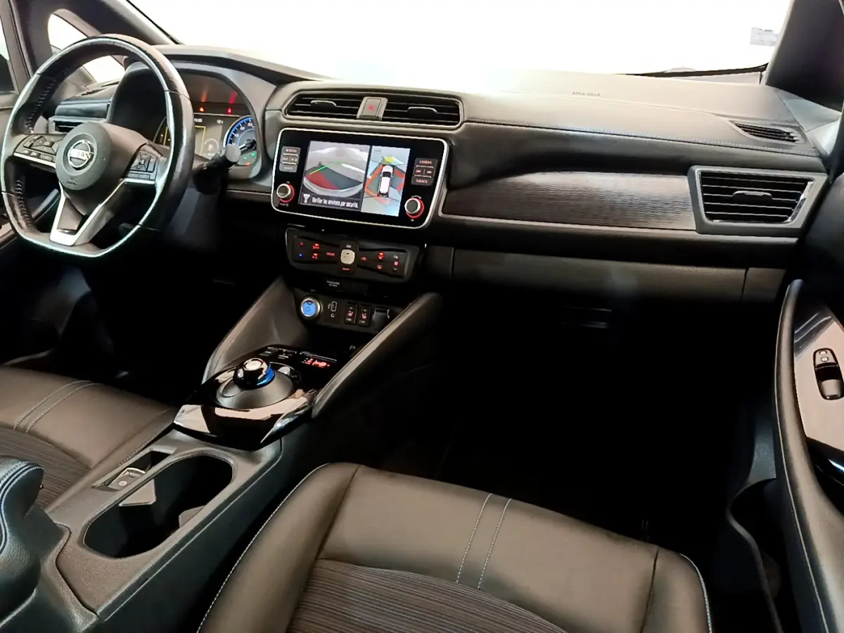 Vue intérieure côté conducteur du tableau de bord noir du Nissan Leaf 62 kWh avec écran tactile et volant cuir multifonctions.