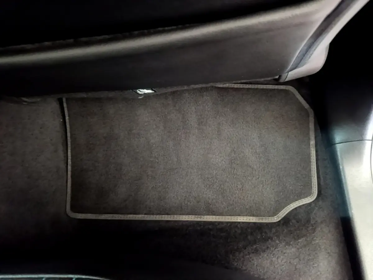 Tapis de sol noir côté passager avant dans l'habitacle d'une Nissan Leaf blanche 2020.