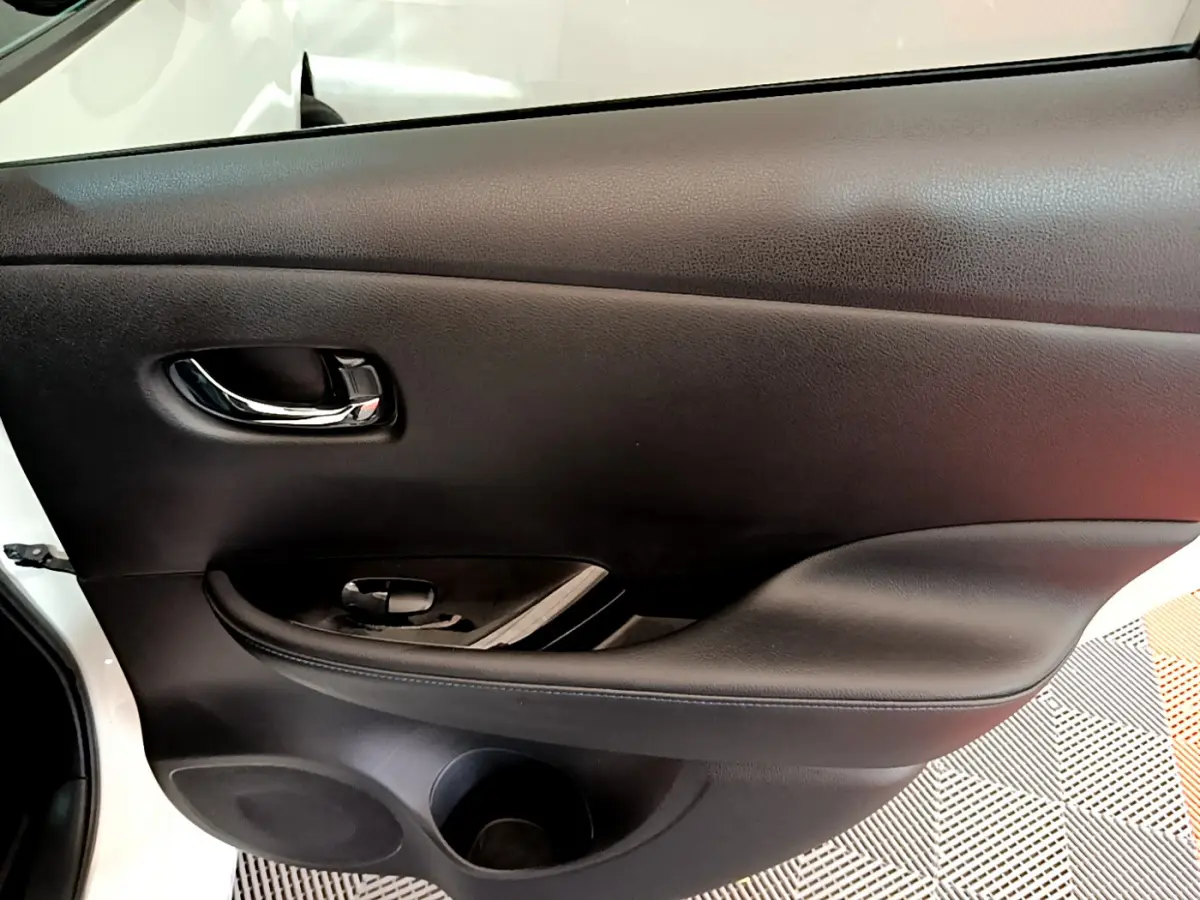 Gros plan sur la porte intérieure côté conducteur noire du Nissan Leaf blanc 2020, avec poignée chromée et commande de vitre.