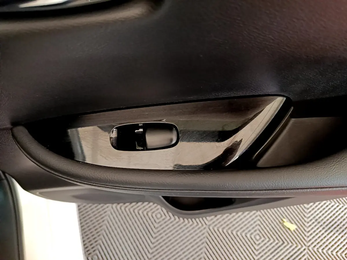 Poignée intérieure côté gauche en plastique noir brillant dans une Nissan LEAF 62 kWh Business+ blanche de 2020.