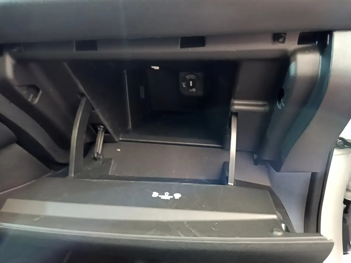 Gros plan sur la boîte à gants ouverte du Nissan Leaf blanc 2020, montrant une prise 12V à l'intérieur.