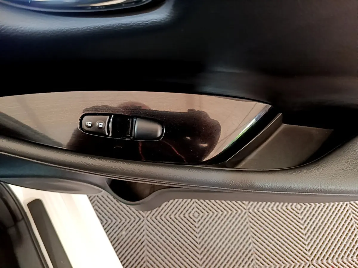 Gros plan sur la commande de verrouillage des portes côté conducteur d'une Nissan Leaf blanche, intérieur noir.